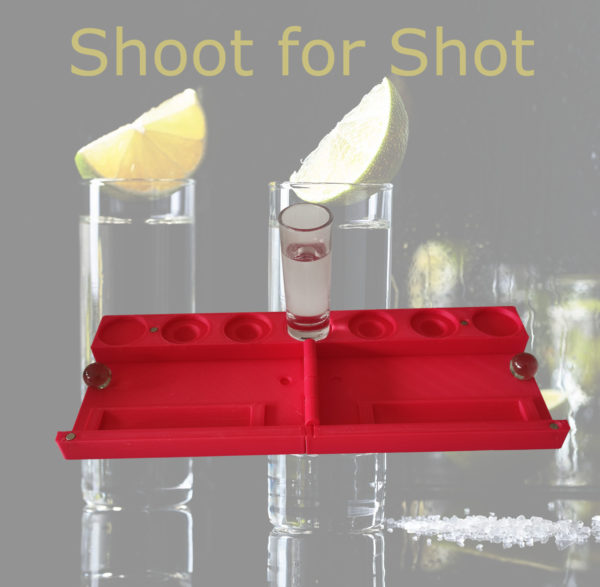 Zwei Personen spielen das "Shoot for Shot" Trinkspiel, wobei eine Person gerade ihre Murmel ins Ziel schießt.