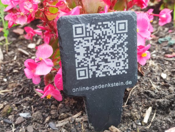Physischer Gedenkstein aus Schiefer mit eingraviertem QR-Code, der zur persönlichen Online-Trauerseite führt.